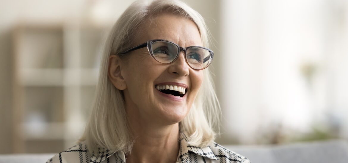 mature woman smiling on a couch, showing new dental implants