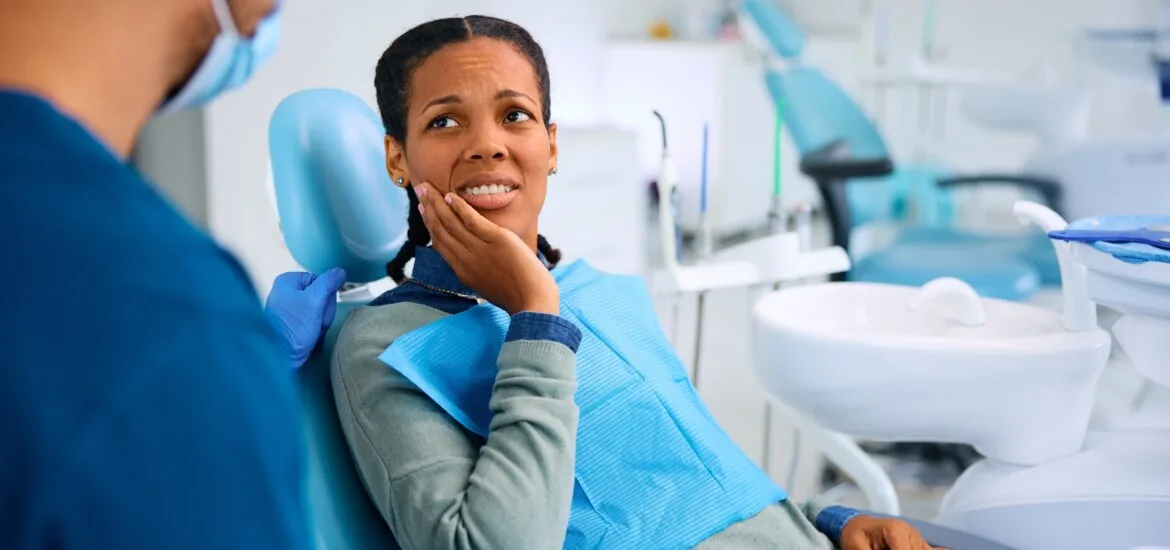 young woman sitting in a dental chair with severe tooth pain