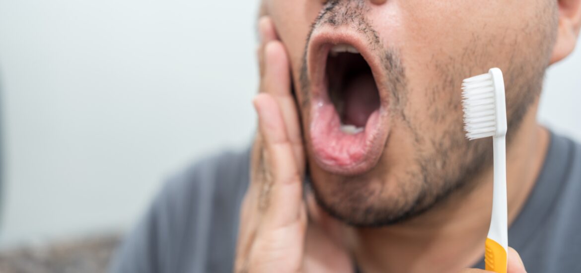 man brushing his teeth in the mirror, tooth pain