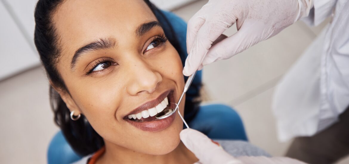 smiling woman, having her teeth worked on by dentist in white gloves